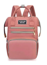 Pink baby travel bag with front zip pockets, top handles, and grey strap