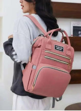 Pink baby travel bag worn on shoulder, with front zip pocket and top handles