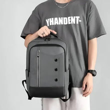 Gray travel backpack with padded straps and front zip pocket, held in front.